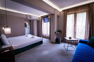 a hotel room with a bed and a blue couch at Вила АРБОРЕТУМ - онлайн self check-in in Teteven