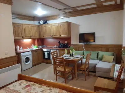 a kitchen and living room with a table and a couch at Private Studio Pirin Golf Hotel Bansko in Razlog