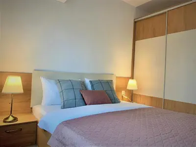 a bedroom with a large bed with blue and purple pillows at Gardenia Apartments in Sofia