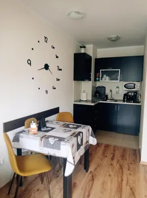 a kitchen with a table and chairs and a clock on the wall at Апартамент С-59 в Апарт-хотел Боровец Гардънс in Borovets