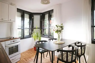 a kitchen with a table and chairs and windows at Modern Cozy Apartment in Kyustendil