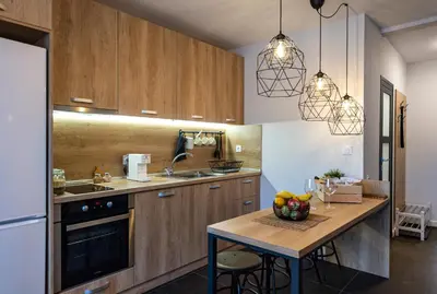 a kitchen with wooden cabinets and a table with a bowl of fruit at Borovete Mountain Luxury in Borovets