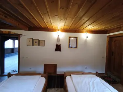 a bedroom with two beds and a wooden ceiling at Къща за гости Кануш войвода in Kovachevitsa