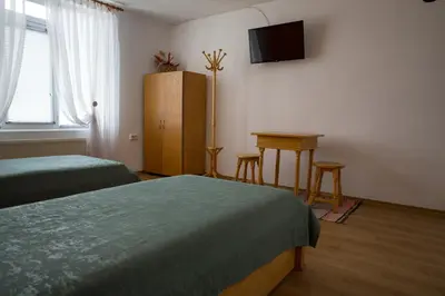 a bedroom with two beds and a table and a television at къща Слави in Oreshak