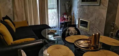 a living room with a black couch and tables at Мирков Дар in Bansko