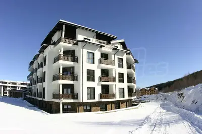 a large white building in the snow with snow at Мирков Дар in Bansko