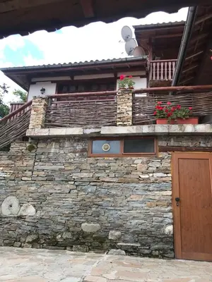 a stone building with a wooden door and a balcony at Sharkov Guest House in Dolen