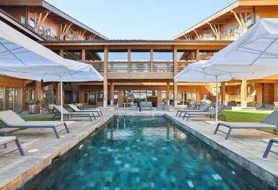 a pool with chairs and umbrellas in front of a building at Pirin Golf Studio Apartment in Razlog