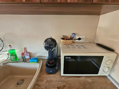 a kitchen counter with a microwave next to a sink at Емили Фемили Хаус in Koprivshtitsa