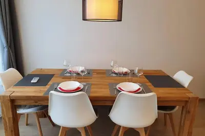 a dining room table with white chairs and a wooden table at Луксозен апартамент с WiFi на 10км от Боровец in Samokov