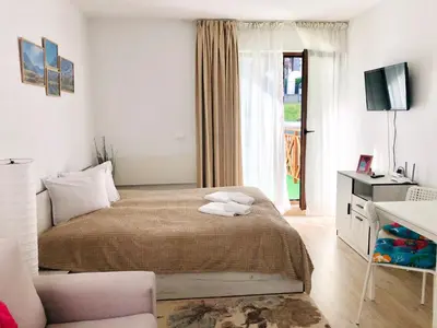 a bedroom with a bed and a tv and a window at Temerso Studio-Apartment in Bansko