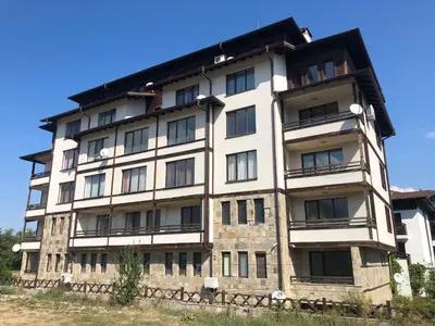 a tall white building with a black roof at Nickmar Studio-Apartment in Bansko