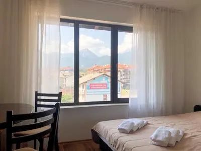 a bedroom with a bed and a table and a window at Nickmar Studio-Apartment in Bansko