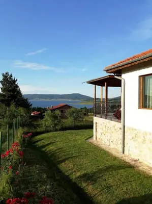 a house with a balcony and a yard with flowers at Вили Green in Tsigov Chark