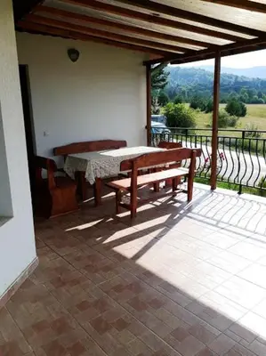 a patio with a table and benches on a balcony at Вили Green in Tsigov Chark