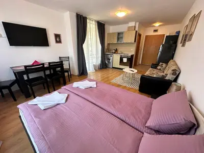 a living room with a large pink bed and a kitchen at Aspen Golf - private apartments in Razlog