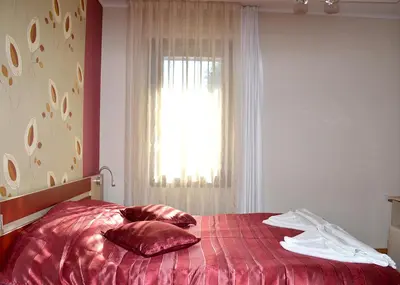 a bedroom with a red bed with a window at Къщи за гости 