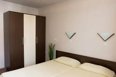 a bedroom with a bed with a wooden headboard at Апартамент DIMANI-Апартхотел Форест Нук Пампорово in Pamporovo