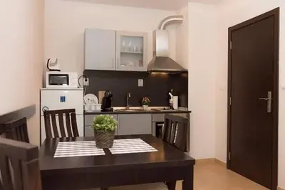 a kitchen with a table with chairs and a kitchen with a sink at Апартамент DIMANI-Апартхотел Форест Нук Пампорово in Pamporovo