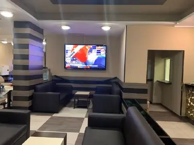 a waiting room with couches and a tv on a wall at Borovets Green Hotel in Borovets