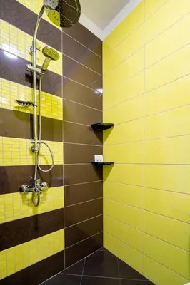 a bathroom with a shower with yellow and brown tiles at Cozy little apartment in Studentski grad in Sofia