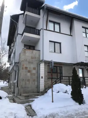 a white building with snow in front of it at Marina Apartment in Bansko