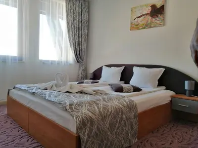 a bedroom with a large bed with white sheets at GRAND MONASTERYl Apartment ``Star Paradise`` in Pamporovo