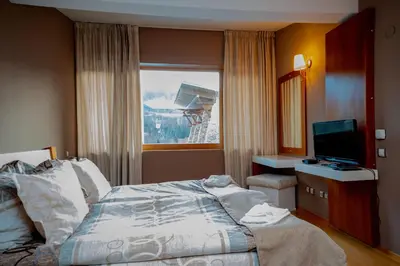a bedroom with a bed and a television and a window at Luxury houses in Dobrinishte in Dobrinishte