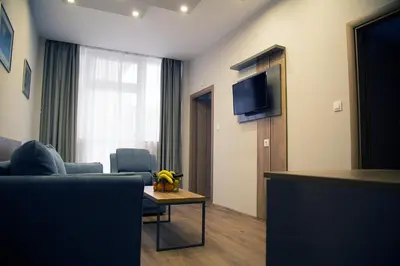 a living room with a couch and a table and a tv at AquaSun Family Hotel in Sandanski