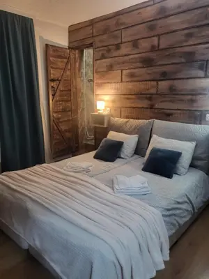 a bedroom with a large white bed with a wooden wall at Boina House in Bansko