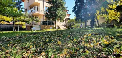 a house with a lot of leaves on the grass at ALBISTO Dragalevtsi Luxury Apartments in Sofia