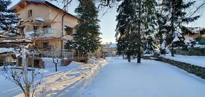 a house is covered in snow with trees and a yard at ALBISTO Dragalevtsi Luxury Apartments in Sofia