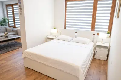 a white bedroom with a white bed and two tables at Shushi's Central Studio Apartment in Plovdiv
