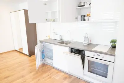 a kitchen with white cabinets and a wooden floor at Shushi's Central Studio Apartment in Plovdiv