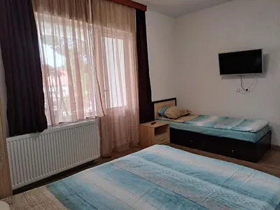 a bedroom with two beds and a tv and a window at Вила Слънчев Бряг in Dospat