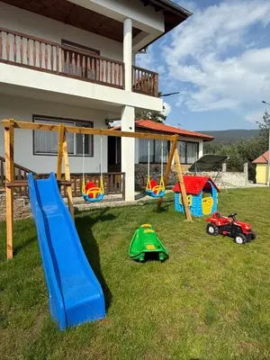 a yard with playground equipment in front of a house at Вила Слънчев Бряг in Dospat