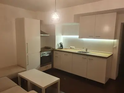 a kitchen with white cabinets and a sink and a table at The white apartment at the ski in Bansko