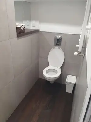 a small bathroom with a toilet and a wooden floor at The white apartment at the ski in Bansko