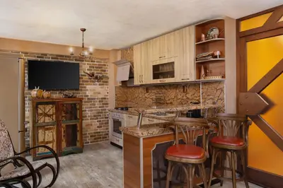 a kitchen with a bar with stools and a tv at Къща за гости