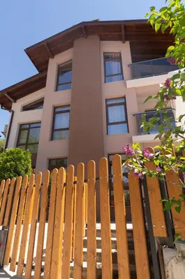 a wooden fence in front of a house at Къща за гости