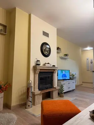 a living room with a fireplace and a clock on the wall at Апартамент Liora in Smolyan