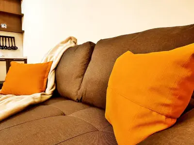 a brown couch with two orange pillows on it at Приказното място - The Fairytale Place in Smolyan