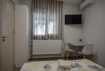 a bedroom with a bed and a table and a window at Къща за гости Фолис in Kyustendil