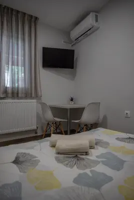 a bedroom with a bed and a table with chairs at Къща за гости Фолис in Kyustendil