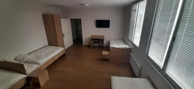 a room with two beds and a table and windows at Hostel Iliana Общежитие Илияна in Elin Pelin