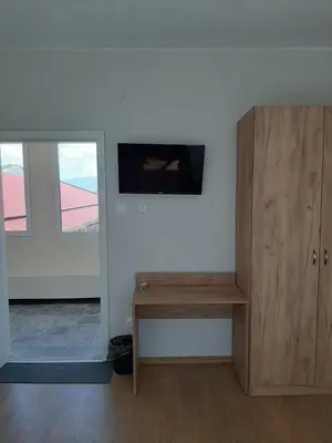 a living room with a table and a wooden cabinet at Hostel Iliana Общежитие Илияна in Elin Pelin