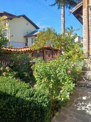a garden with bushes and flowers in front of a house at Guest rooms Bansko in Bansko