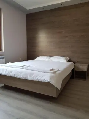 a bedroom with a large bed with a wooden headboard at Апартаменти Гювийски in Sapareva Banya