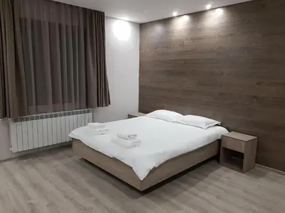 a bedroom with a white bed and a wooden wall at Апартаменти Гювийски in Sapareva Banya