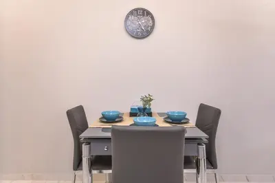 a dining room table with chairs and a clock on the wall at Stylish Residential Flat - with Parking & Balcony by Flat Mаnager in Sofia